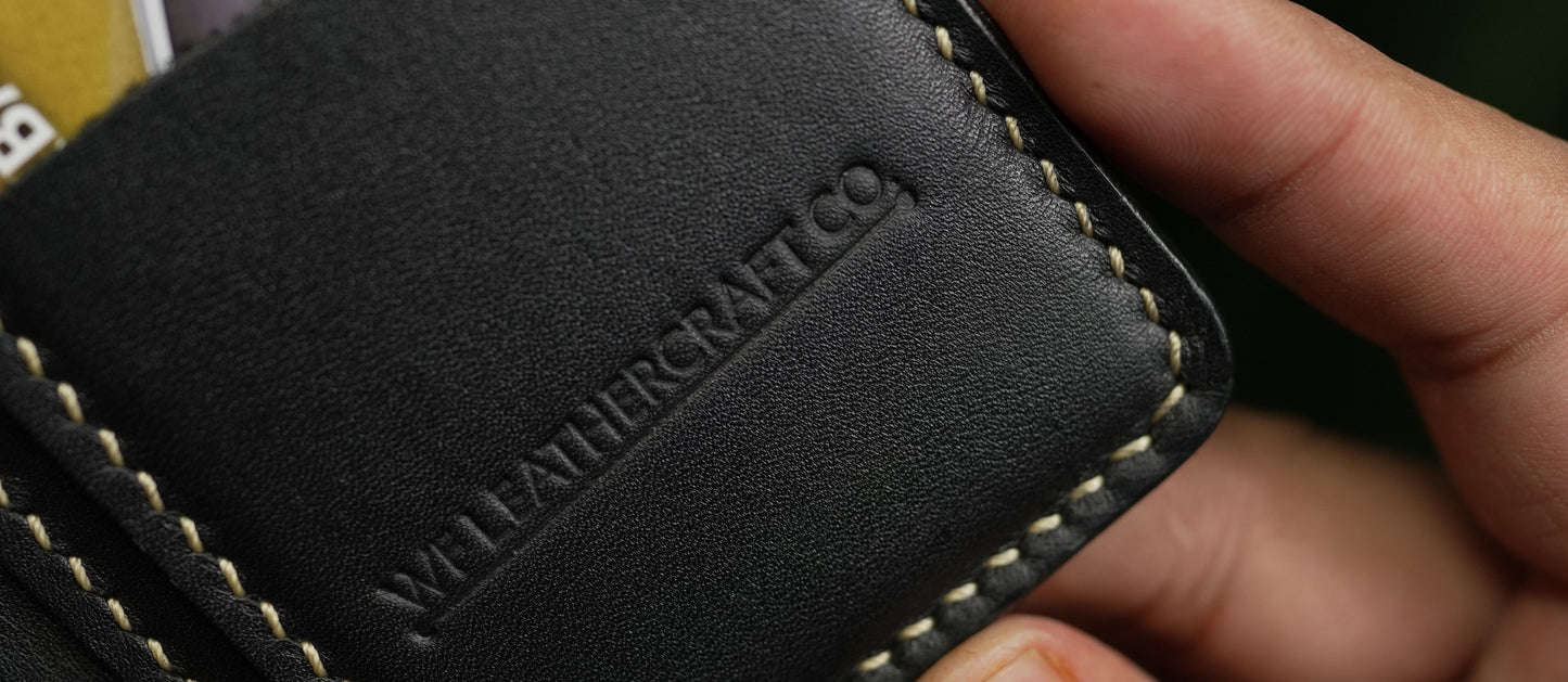 Black leather wallet with brand name held by a hand, with blurred cardholder in the background